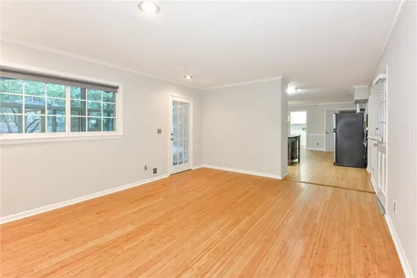 a view of empty room with wooden floor and a window