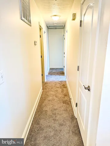 a view of a hallway with wooden floor and a bathroom