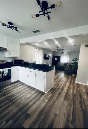 a large white kitchen with stainless steel appliances granite countertop a stove and a wooden floors