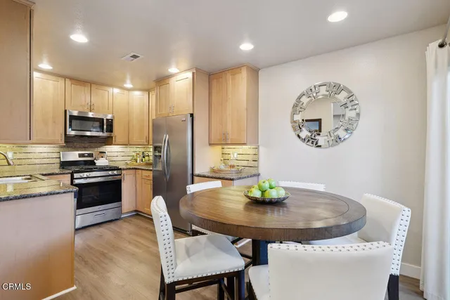 a kitchen with stainless steel appliances granite countertop a kitchen island a stove a table and chairs