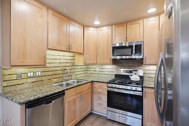 a kitchen with stainless steel appliances granite countertop a sink stove and cabinets
