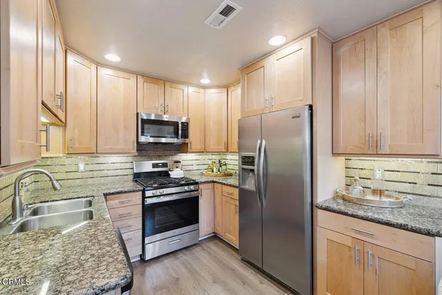 a kitchen with granite countertop stainless steel appliances a refrigerator stove and sink