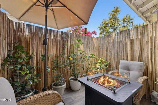 a backyard of a house with table and chairs under an umbrella