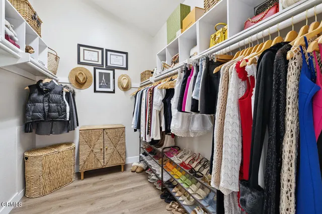 a view of walk in closet with clothes and shoes