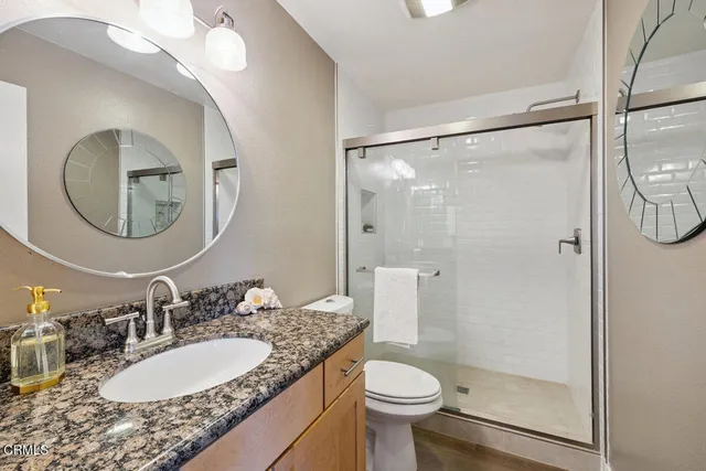 a bathroom with a granite countertop sink mirror toilet and shower