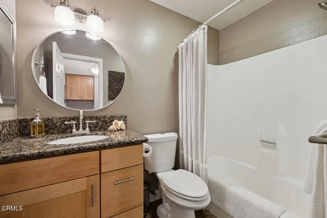 a bathroom with a granite countertop sink mirror vanity and toilet