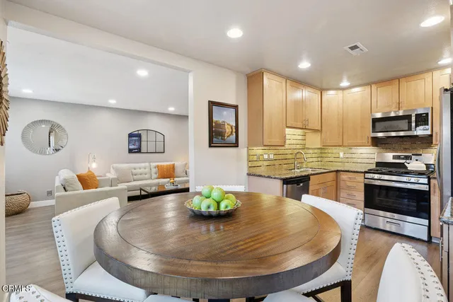 a kitchen with stainless steel appliances wooden floor dining table and chair