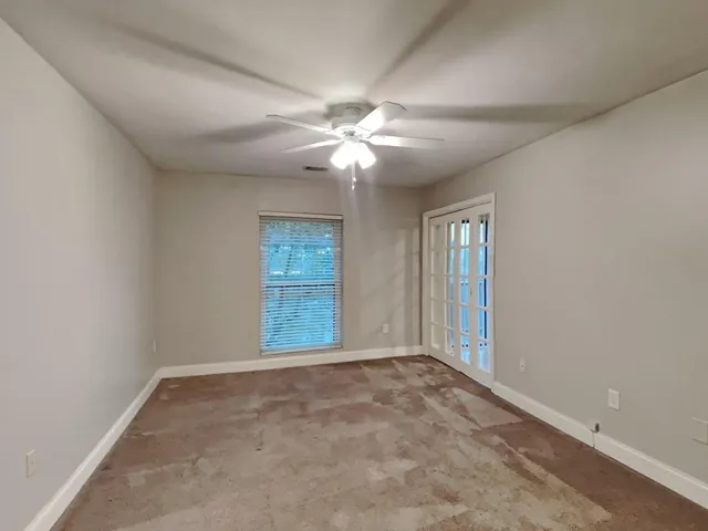 an empty room with windows and fan