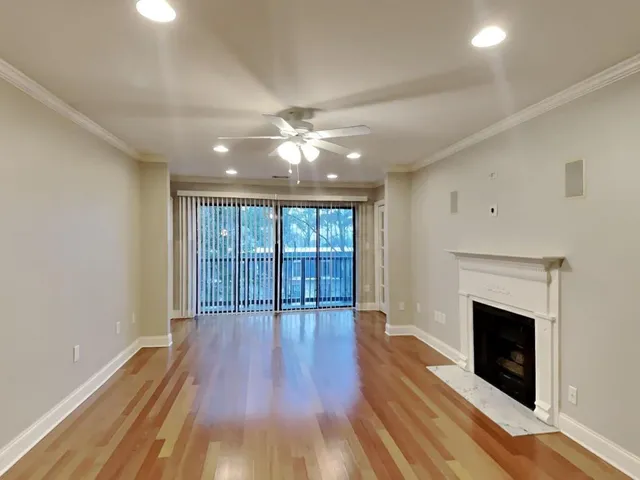 a view of an empty room with wooden floor and a fireplace