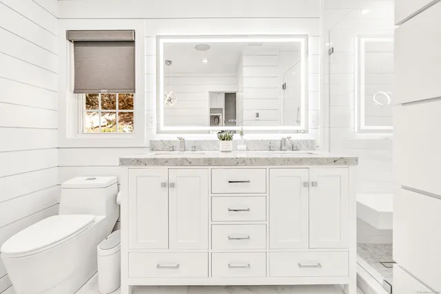 a bathroom with a granite countertop toilet sink and mirror
