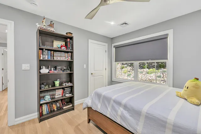 a bedroom with a bed a large window and book shelf