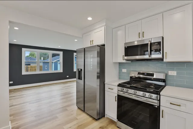 a kitchen with stainless steel appliances white cabinets a stove a microwave and a refrigerator