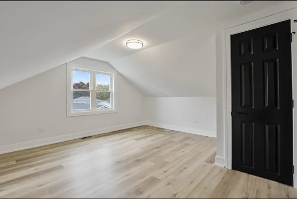 an empty room with wooden floor cabinet and windows
