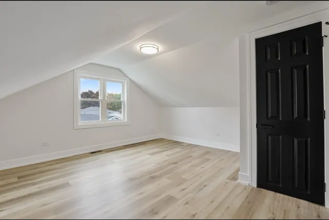 an empty room with wooden floor cabinet and windows