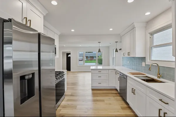 a large kitchen with stainless steel appliances kitchen island granite countertop a refrigerator and a sink