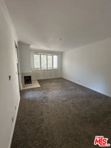 an empty room with windows and fireplace