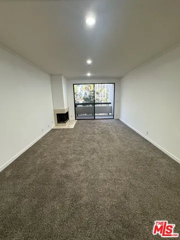 an empty room with windows and fireplace
