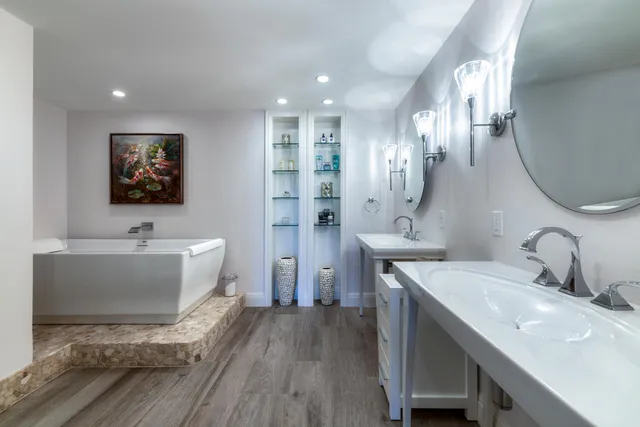 a spacious bathroom with a double vanity sink a mirror a bathtub and a shower
