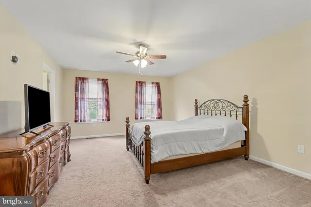 a spacious bedroom with a bed and a flat screen tv on dresser