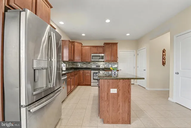 a kitchen with kitchen island granite countertop wooden cabinets a sink a stove a refrigerator and a granite counter tops