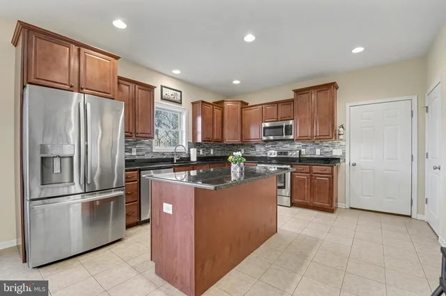 a kitchen with granite countertop a refrigerator sink and cabinets