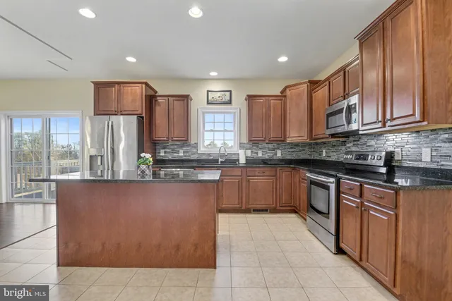 a kitchen with stainless steel appliances granite countertop a refrigerator and a stove top oven