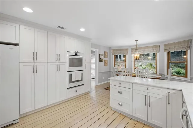 a kitchen with white cabinets and wooden floors