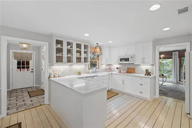 a kitchen with wooden floors and white cabinets