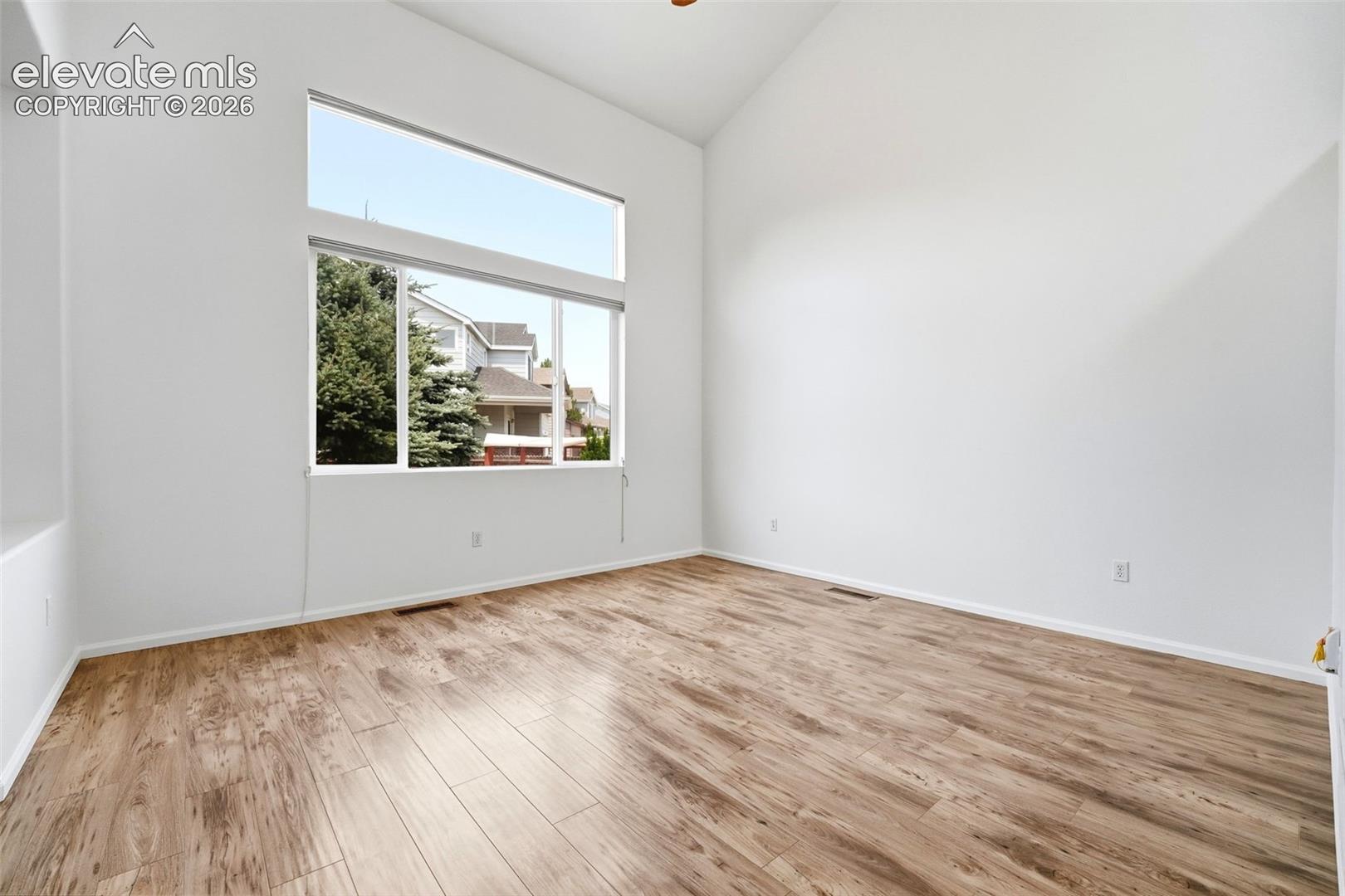 7904 Coffee Road Peyton, CO 80831 - Photo 3 of 48 Spacious room featuring vaulted ceilings, expansive window array, wood-finish flooring, and white baseboards