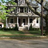 a front view of a house with a garden and trees