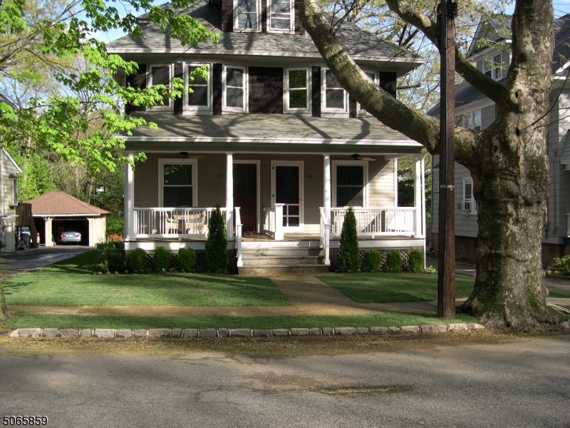 a front view of a house with a garden and trees