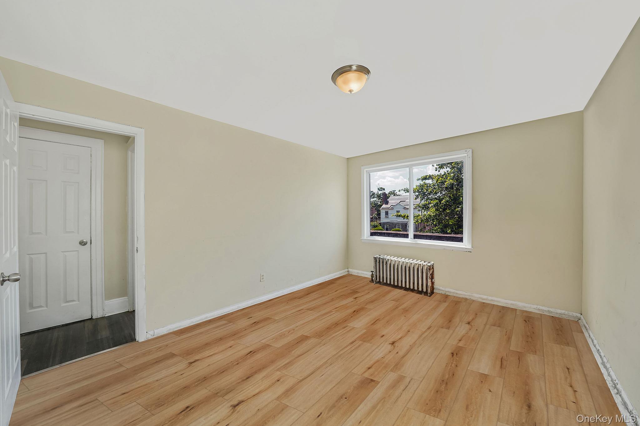 138-41 230th Place Queens, NY 11413 - Photo 13 of 17 a view of an empty room with wooden floor and a window