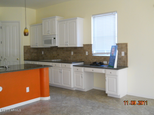20864 West Ridge Road Buckeye, AZ 85396 - Photo 24 of 37 a kitchen with stainless steel appliances granite countertop a sink a stove and white cabinets