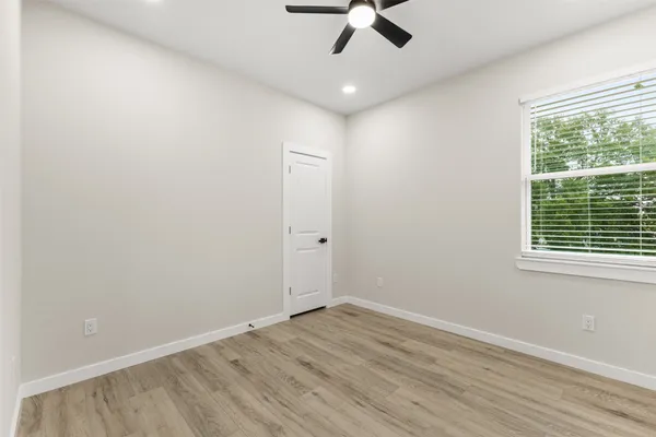 a view of an empty room with a window and wooden floor