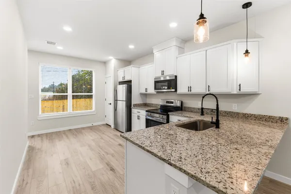 a kitchen with a refrigerator a stove top oven and wooden floors