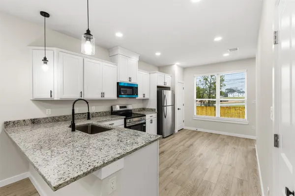 a kitchen with stainless steel appliances granite countertop a sink a stove and a wooden floors