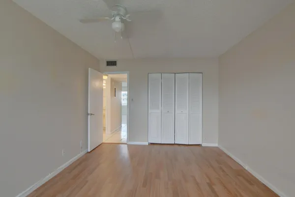 an empty room with wooden floor and fan