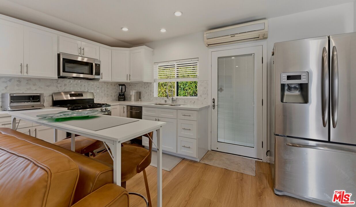 132 North Carson Road, Unit A Beverly Hills, CA 90211 - Photo 6 of 14 a kitchen with stainless steel appliances granite countertop a refrigerator a stove a microwave oven a sink dishwasher and white cabinets with wooden floor