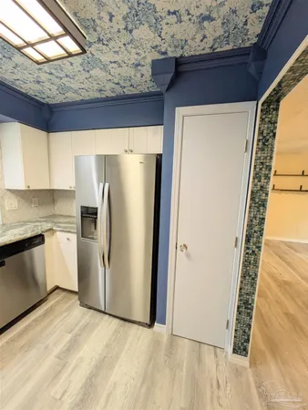 a view of a refrigerator in kitchen and an empty room
