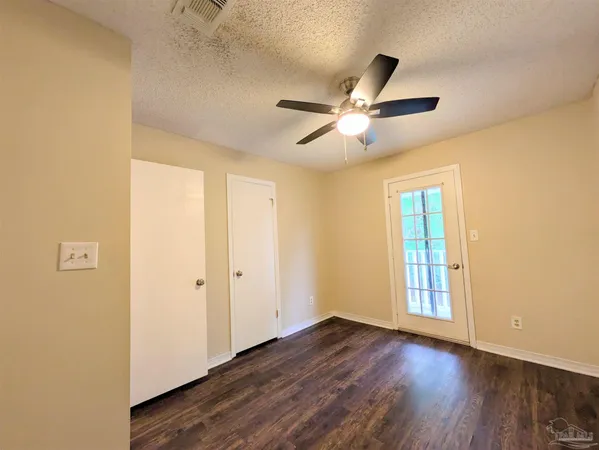 a view of an empty room with wooden floor and a ceiling fan