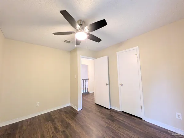 an empty room with wooden floor and a ceiling fan