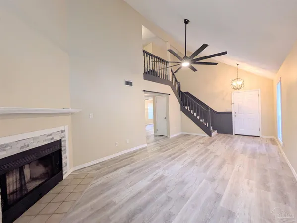 a view of an empty room with wooden floor a fireplace