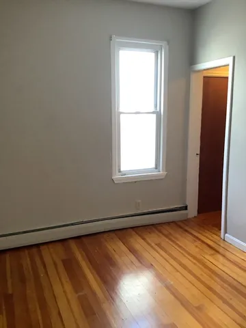 an empty room with wooden floor closet and windows