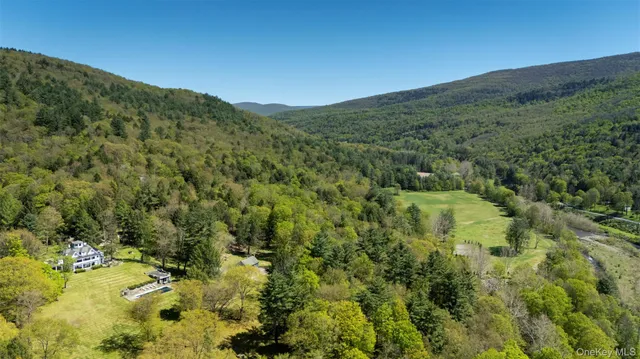 a view of a big house with a big yard and large trees
