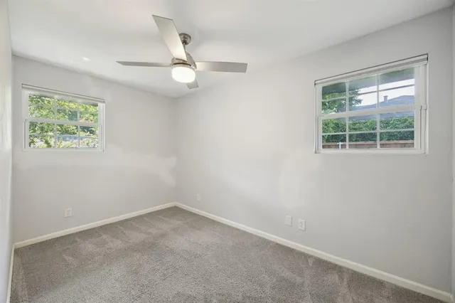 an empty room with a window and ceiling fan