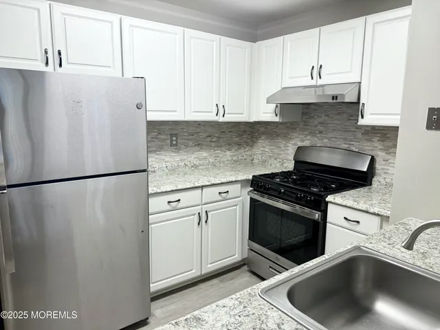 a kitchen with a refrigerator sink and cabinets