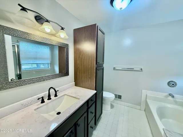 a bathroom with a sink vanity granite toilet tub and shower
