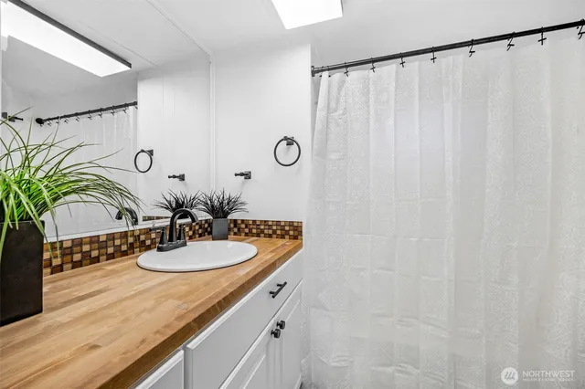 a bathroom with a granite countertop sink a mirror and shower curtain