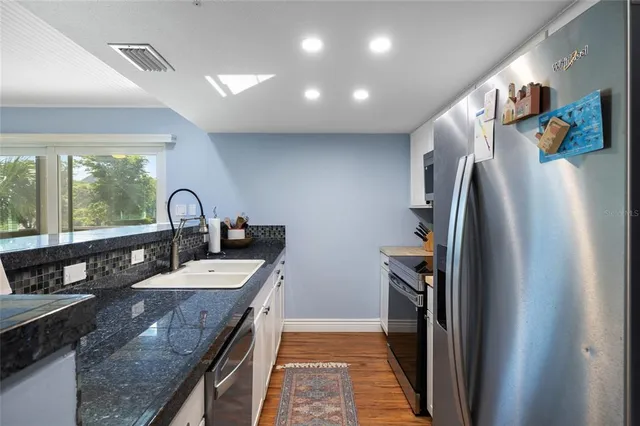 a kitchen with granite countertop a sink and a refrigerator
