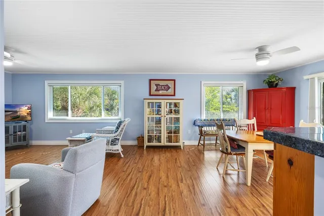 a living room with furniture a large window and wooden floor